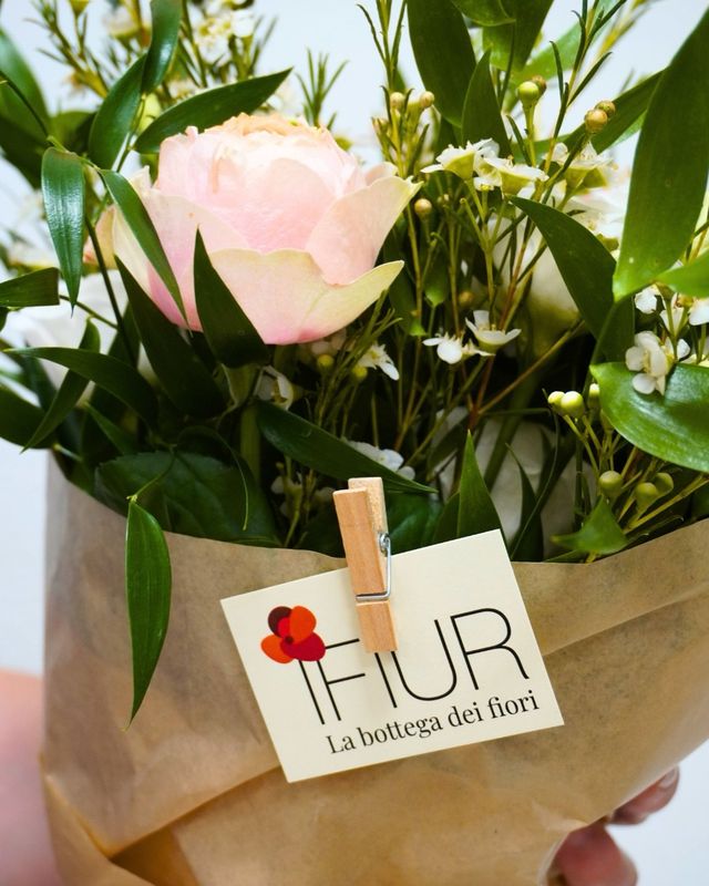 Dettaglio del bouquet con una rosa rosa e il cartellino IFIUR fissato con una molletta di legno